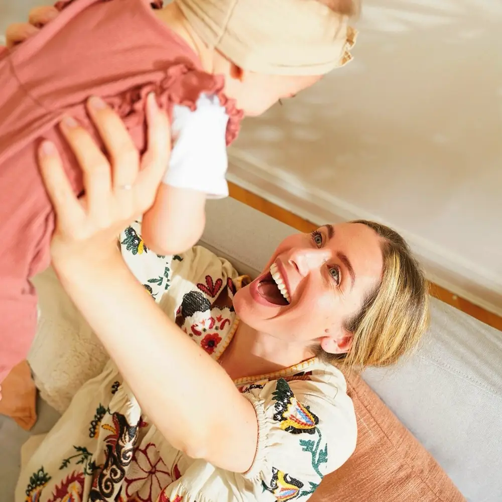 Jess Rose lifting her baby and laughing